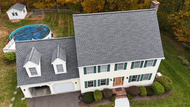Aerial view of a Central Connecticut colonial with a freshly installed charcoal-gray roof by Pattison Construction, surrounded by fall foliage