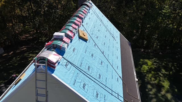 GAF-branded blue waterproof underlayment installed on a Pattison Construction roof deck — visible product branding on every roll