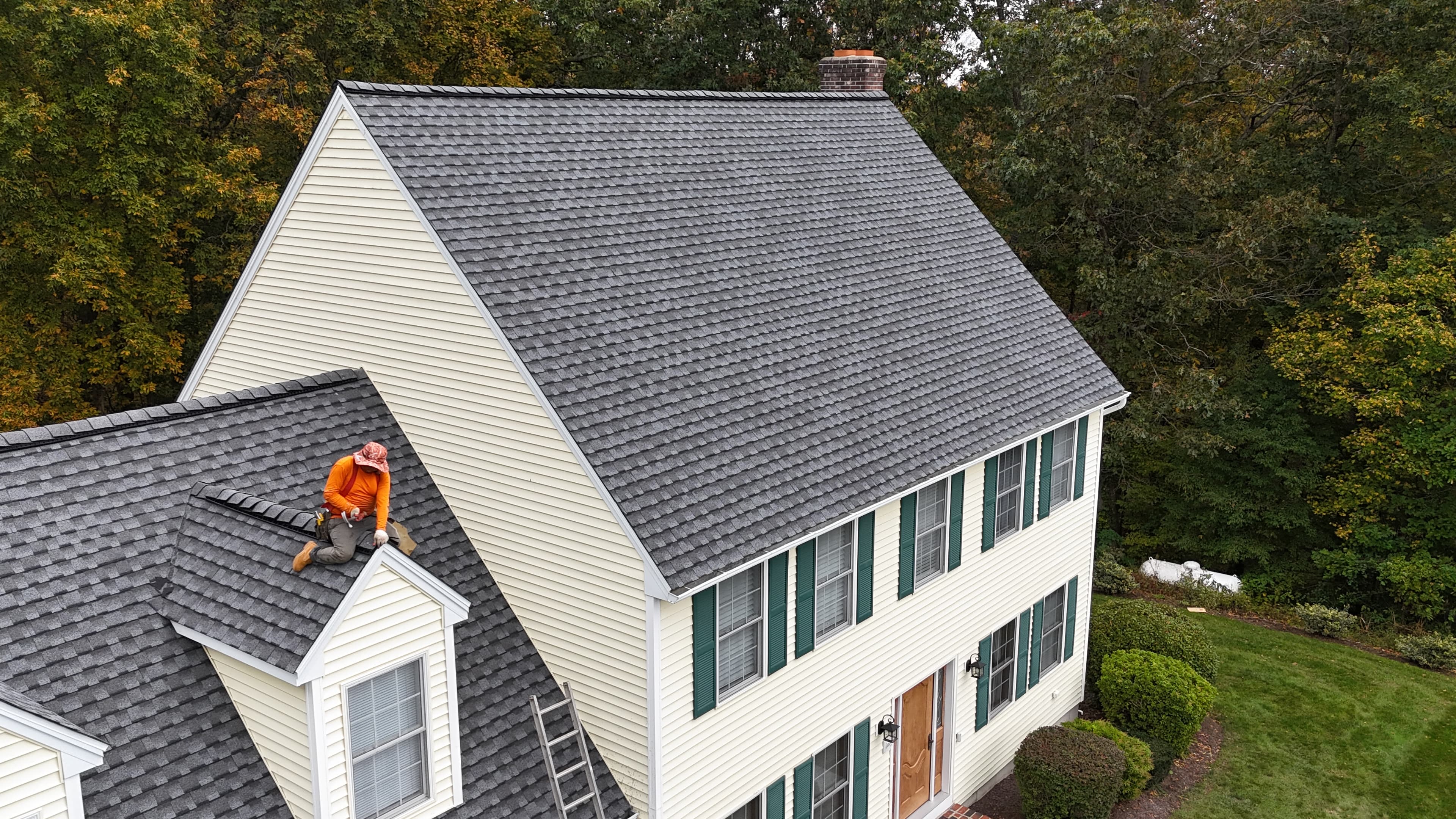 Pattison Construction crew working on a new asphalt-shingle roof on a Connecticut colonial — aerial autumn view
